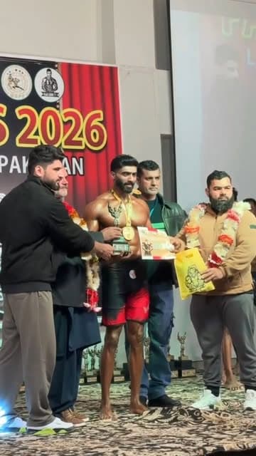 Haris Anjum receiving a trophy at a 2026 bodybuilding competition